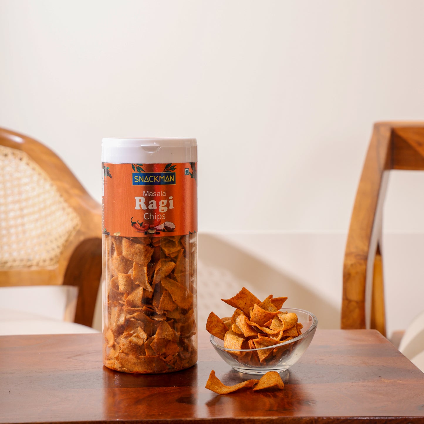 canister of ragi chips with a bowl of chips on a wooden table