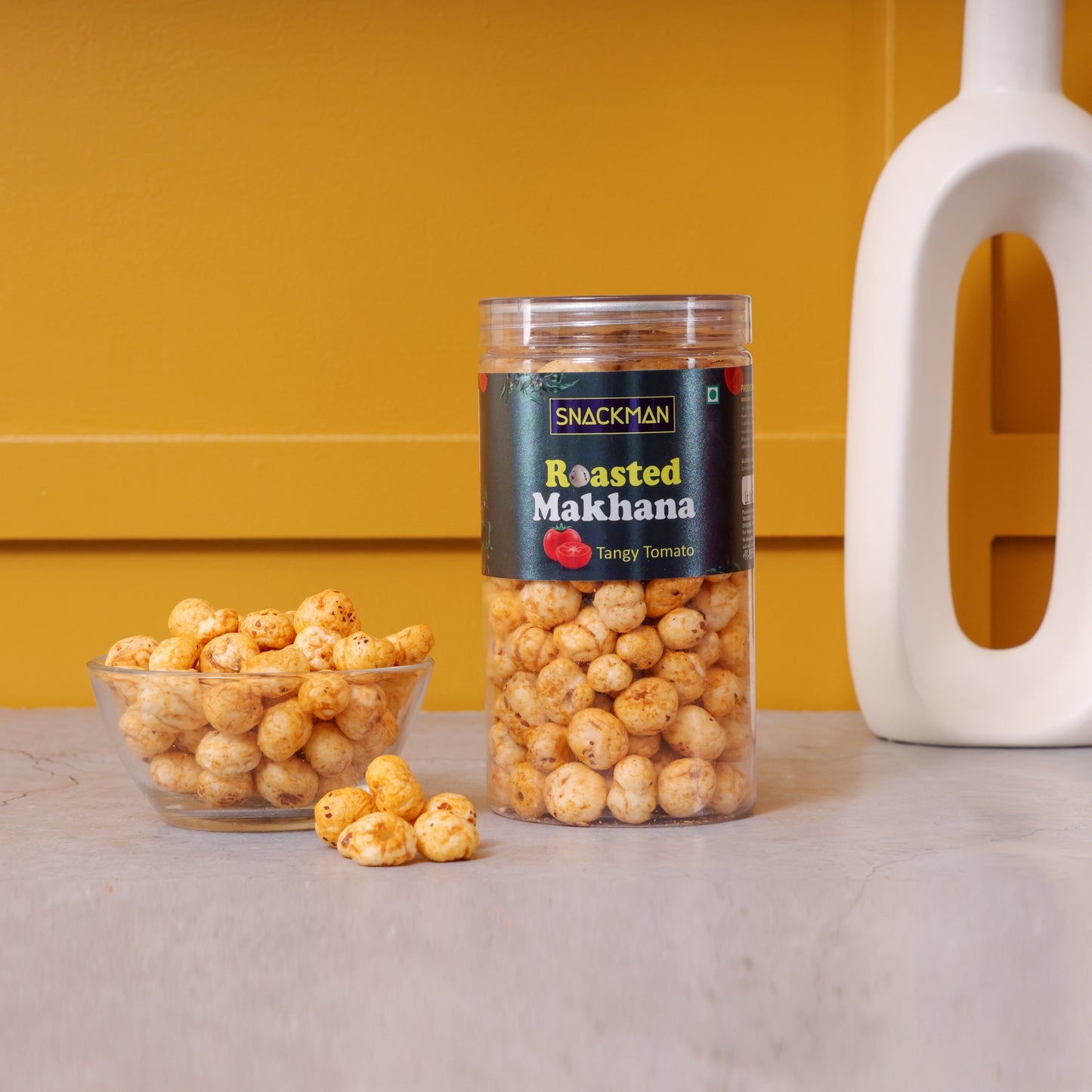 jar of roasted makhana with a bowl of snacks on a yellow background